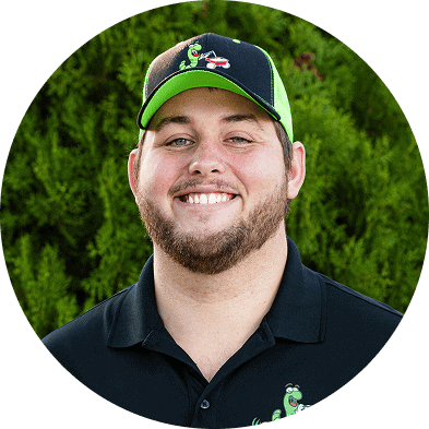 Eco-friendly lawn care professional smiling outdoors with lush greenery, promoting sustainable landscaping services.